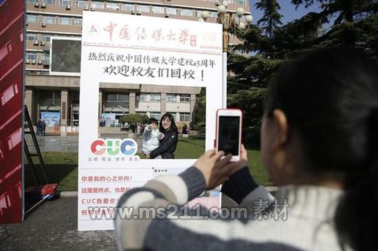中国传媒大学迎来65周年校庆，校友们在纪念板前拍照留念。
